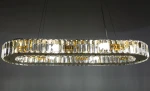 Lampa wisząca Windsor 8xE14 w kolorze złotym, o owalnym kształcie, z przezroczystymi kryształkami. Widoczna struktura z metalowymi elementami, zawieszona na cienkich linkach. Oświetlenie w środku zapewnia intensywne światło.