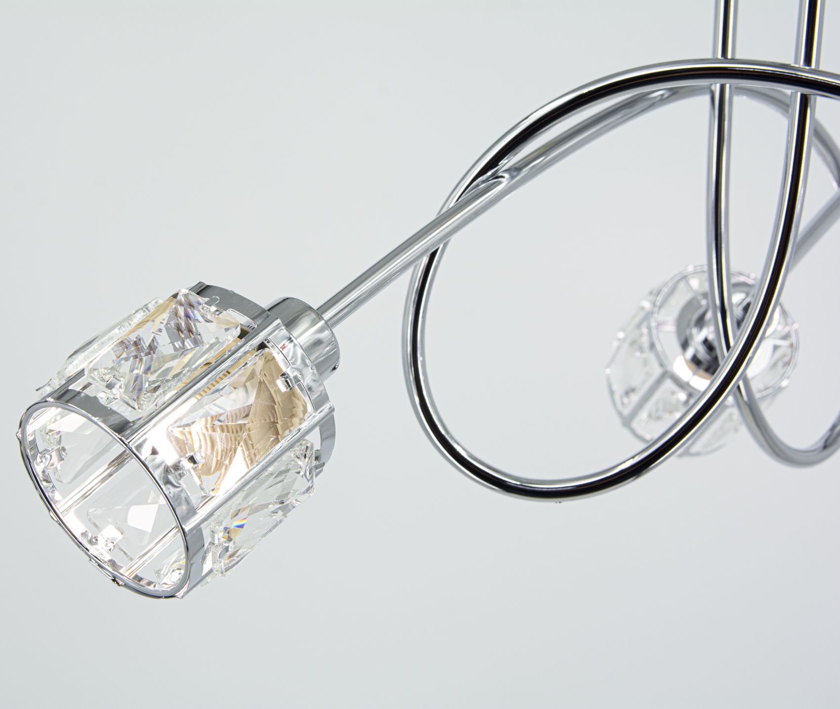 Lampa wisząca Aurora 3xE14 w kolorze chromowanym z dekoracyjnymi kloszami z przezroczystego szkła. Ujęcie z dołu pokazuje eleganckie, zakrzywione ramiona oraz źródła światła. Tło jednolite, co podkreśla nowoczesny design.
