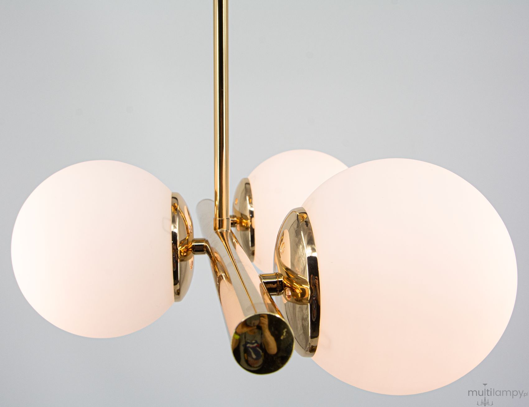 Lampa sufitowa Otis 3xE27 w złotym wykończeniu, z trzema okrągłymi kloszami z matowego szkła. Ujęcie z góry, pokazujące detale mocowania i błyszczące elementy metalowe. Produkt zawieszony, na jednolitym tle.