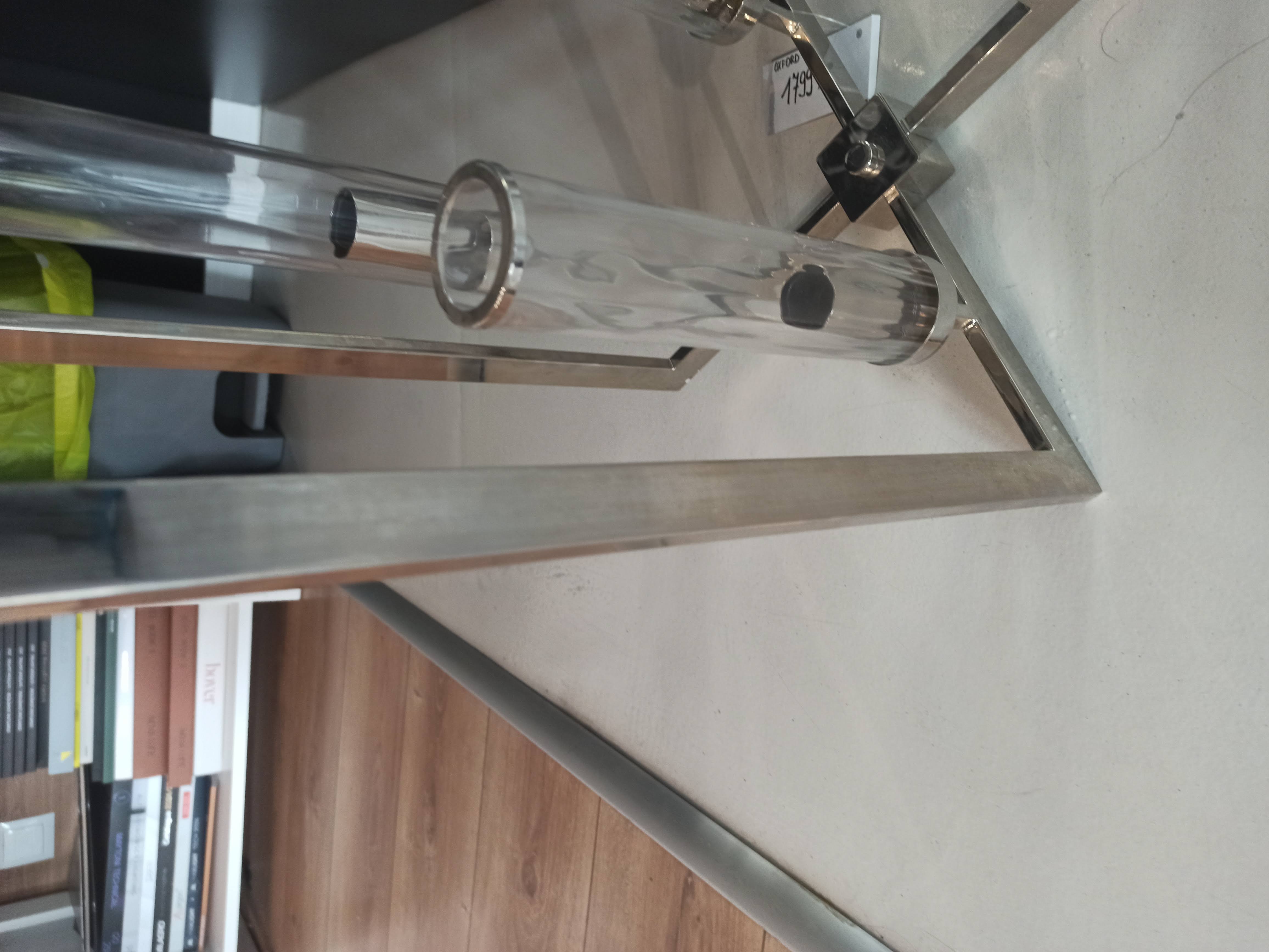 Lampa wisząca Oxford 4-punktowa P04052NI z metalową, stalową ramą, szklanymi kloszami w formie cylindrów. Ujęcie z boku, ukazujące detale mocowania i przezroczystych elementów. Tło neutralne, z widocznymi książkami i pojemnikiem.