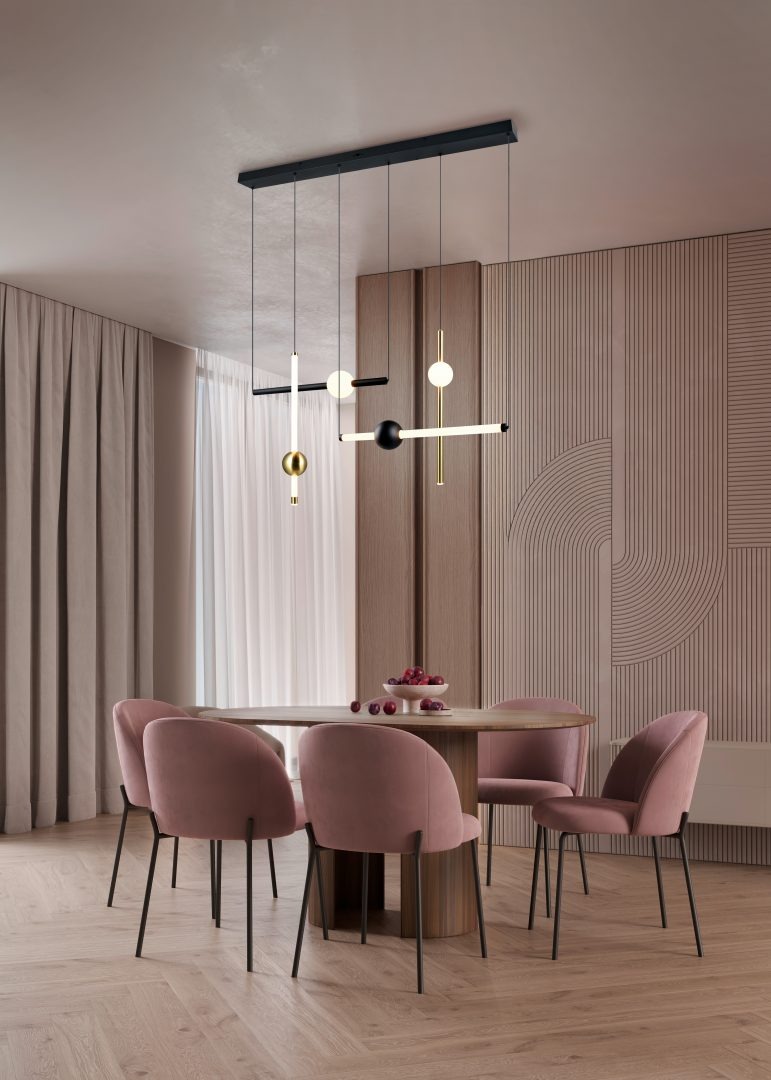 Lampa wisząca Melita z czterema źródłami LED 21W CCT, w kolorze czarnym i złotym. Produkt zawieszony na długich przewodach, z minimalistycznym designem, w otoczeniu jasnych zasłon i różowych krzeseł przy drewnianym stole.