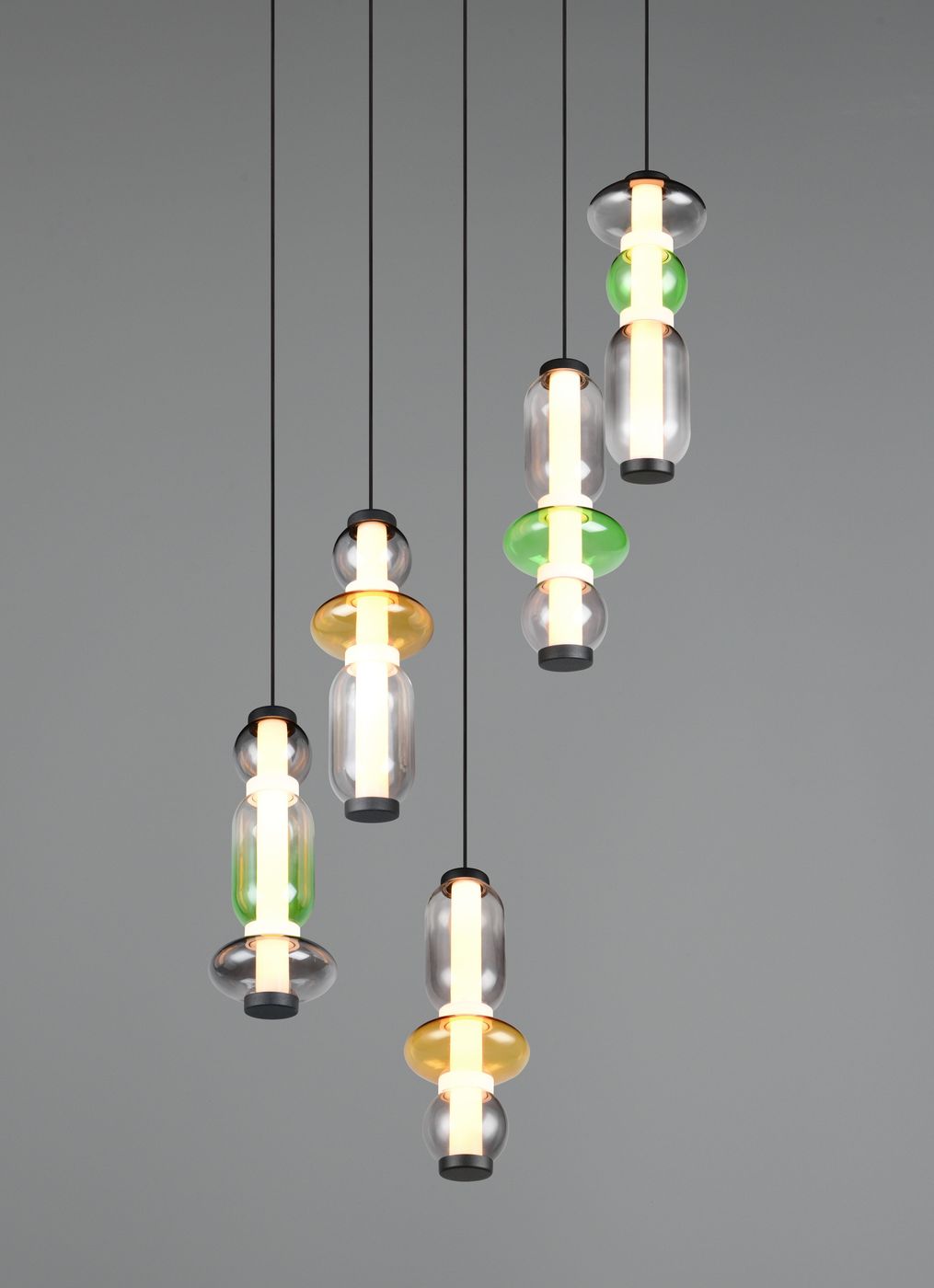 Lampa wisząca Minerva 5xLED 40W CCT w kolorze czarnym, z pięcioma szklanymi kloszami w różnych kolorach (zielony, żółty, przezroczysty), zawieszona na czarnych linkach, w aranżacji na szarym tle. Idealna do nowoczesnych wnętrz.