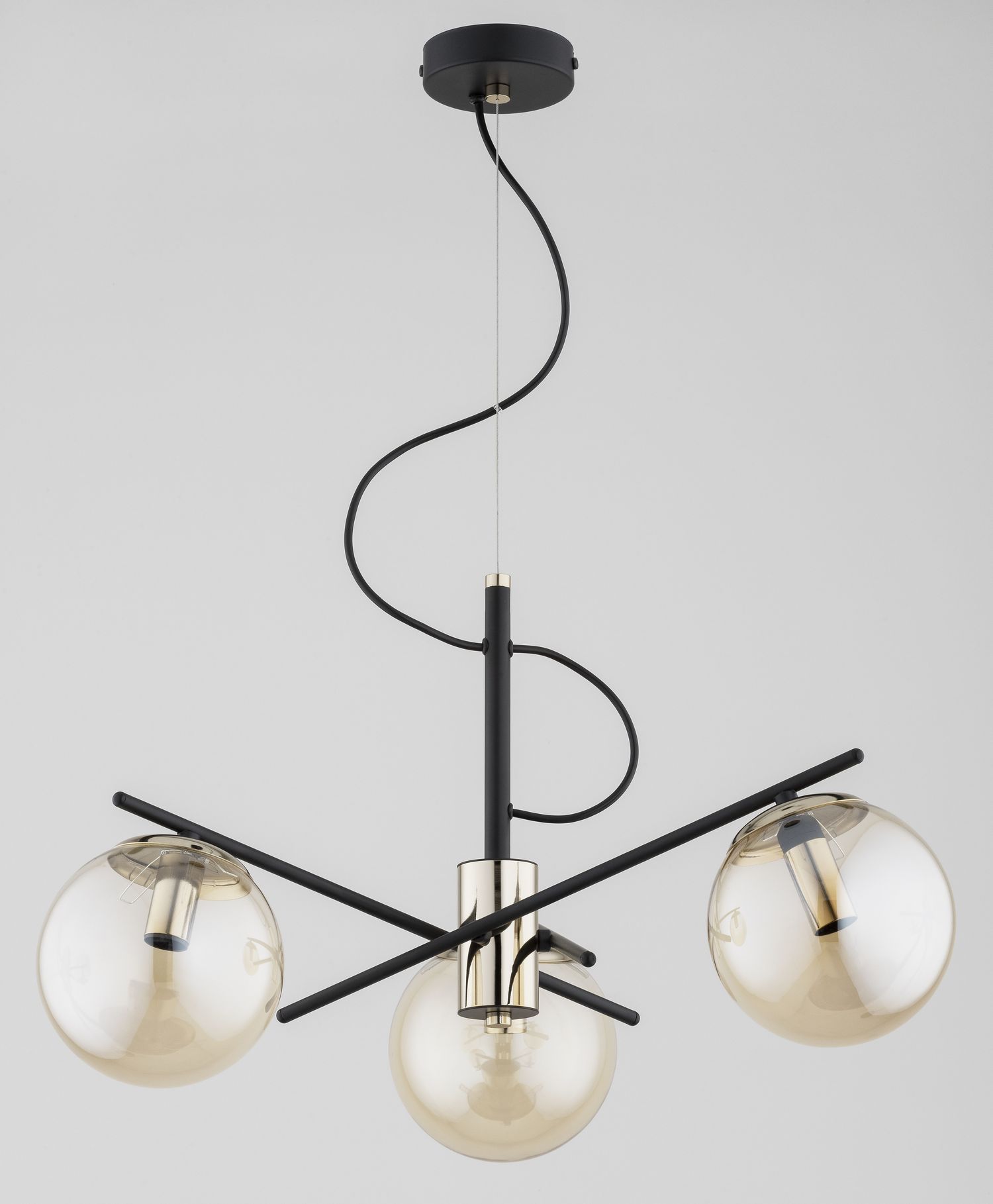 Lampa wisząca Taurus Mix w kolorze czarno-złotym, z trzema kulistymi kloszami z przezroczystego szkła. Ujęcie z dołu, pokazujące elegancką konstrukcję i spiralne przewody. Klosze umieszczone na metalowych ramionach w kształcie krzyża.
