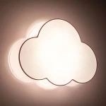 Plafon Cloud w kształcie chmury, pastelowy różowy, z delikatnym podświetleniem. Produkt ma zaokrąglone krawędzie, wykonany z tworzywa sztucznego. Ujęcie frontalne, montowany na suficie, idealny do dziecięcego pokoju.