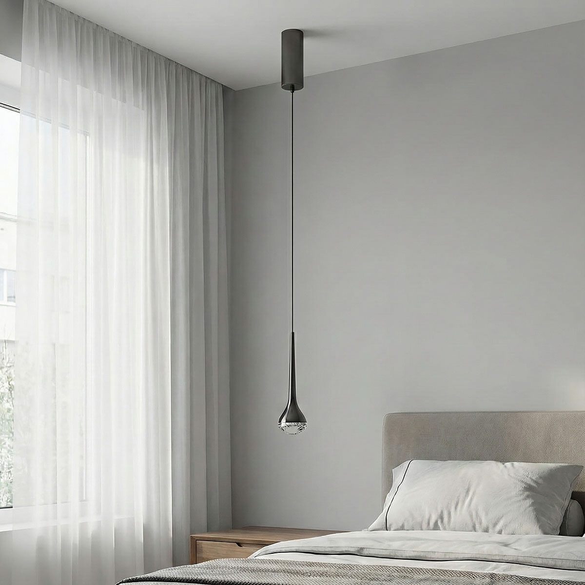 Lampa wisząca Crima Nero LED o nowoczesnym designie, w kształcie smukłego stożka, w kolorze czarnym. Zawieszona na cienkim przewodzie, umieszczona nad łóżkiem w jasnym, minimalistycznym wnętrzu z szarymi ścianami i zasłonami.