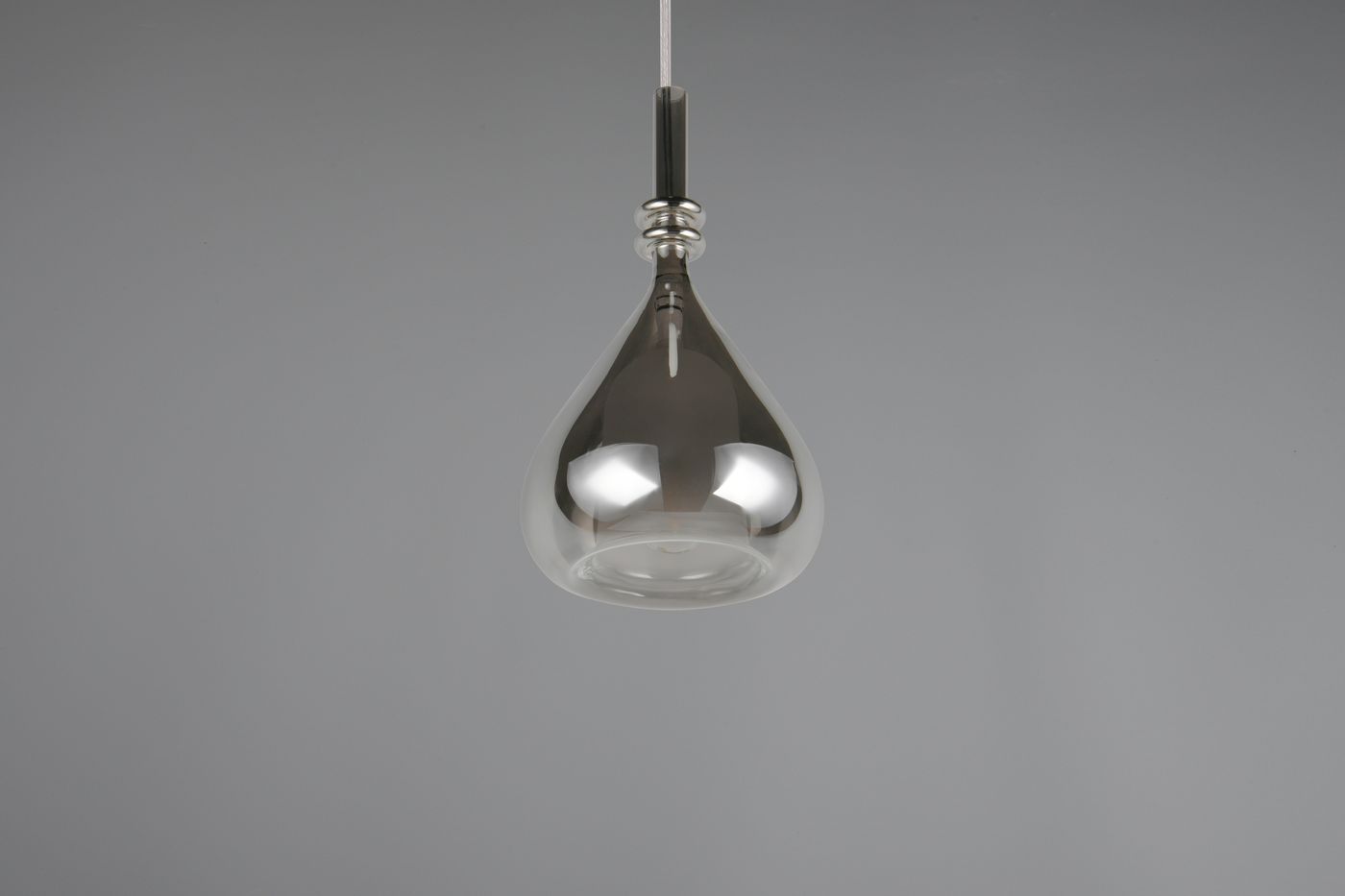 Lampa wisząca Aldea z kloszem w kształcie kropli, wykonana z przezroczystego szkła, z chromowanym mocowaniem. Zawieszona na cienkim, białym przewodzie, idealna do nowoczesnych wnętrz. Wymiary i detale mocowania niewidoczne.