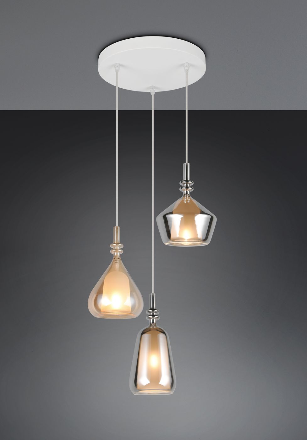 Lampa wisząca Aldea z trzema kloszami w różnych kształtach, wykonana z przezroczystego szkła, zamocowana na białym stelażu. Klosze w kolorze białym, srebrnym i miedzianym, zawieszone na cienkich linkach. Idealna do nowoczesnych wnętrz.