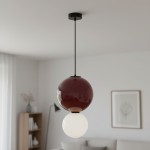 Lampa wisząca LED Pieve D25 o mocy 7W, kolor bordowy, z okrągłym kloszem w górnej części i białą kulą na dole. Zawieszona na cienkim, czarnym przewodzie, w nowoczesnym wnętrzu z jasnymi ścianami i meblami.