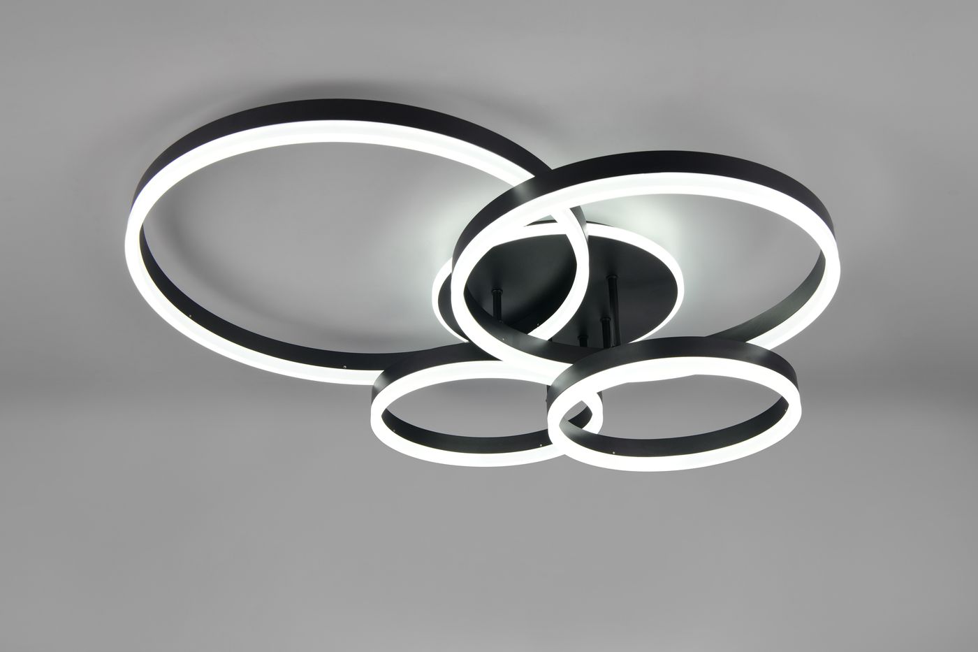 Lampa sufitowa Drake z pilotem, czarna, 5xLED/50W CCT. Składa się z trzech okrągłych pierścieni, z których dwa mają białe podświetlenie. Ujęcie z dołu, produkt zamontowany na suficie. Idealna do nowoczesnych wnętrz.