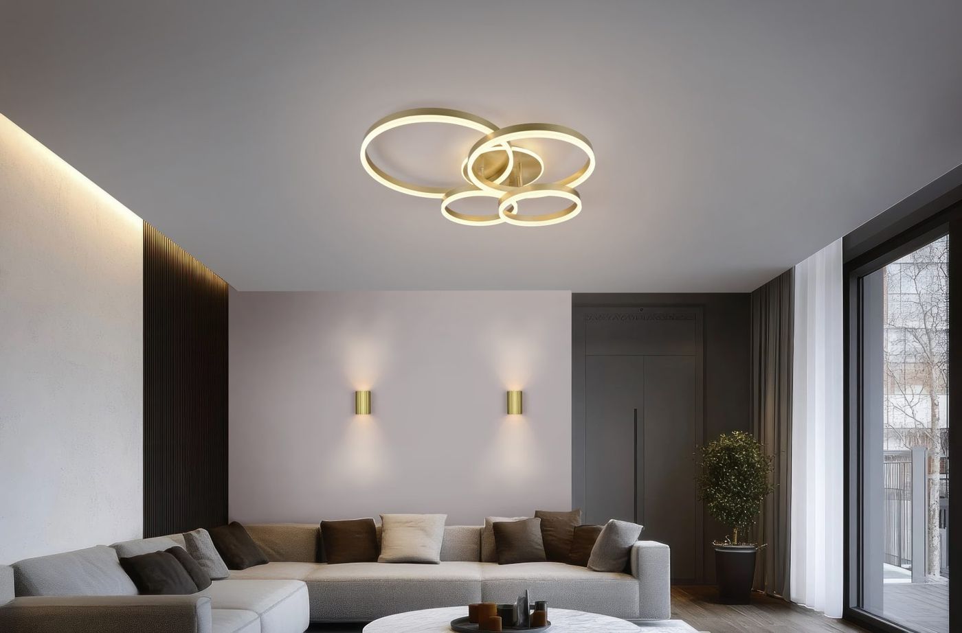 Lampa sufitowa Drake z pięcioma źródłami LED, 50W, w kolorze złotym. Posiada okrągłe, splątane elementy w nowoczesnym designie. Zawieszona na suficie w jasnym wnętrzu, otoczona meblami i dodatkami w neutralnych odcieniach.