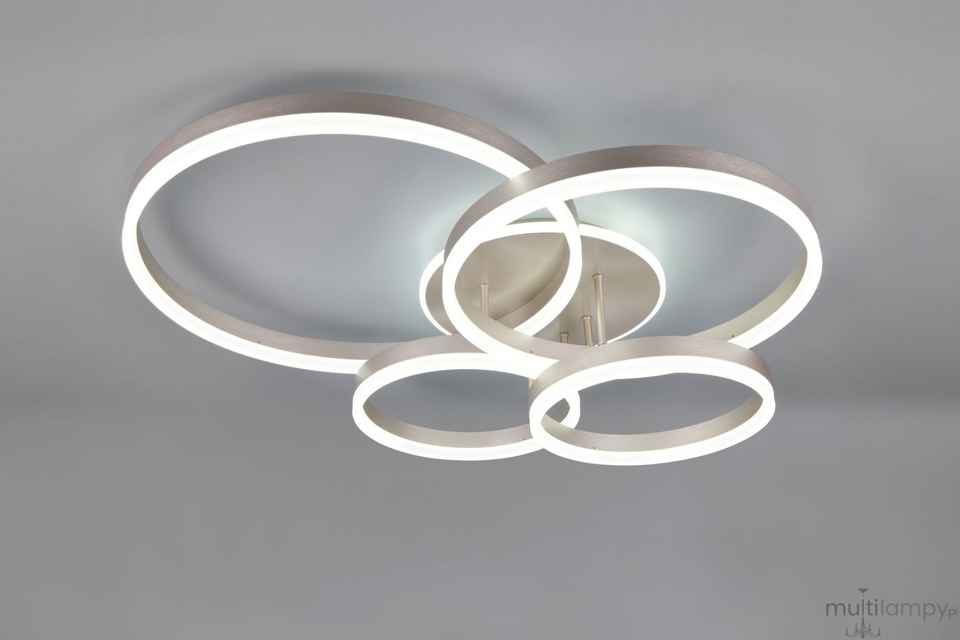Lampa sufitowa Drake w kolorze niklowym z pięcioma pierścieniami LED o mocy 50W. Ujęcie z góry, ukazujące trzy różnej wielkości, delikatnie zaokrąglone pierścienie. Produkt oferuje możliwość zdalnego sterowania. Tło jednolite, szare.