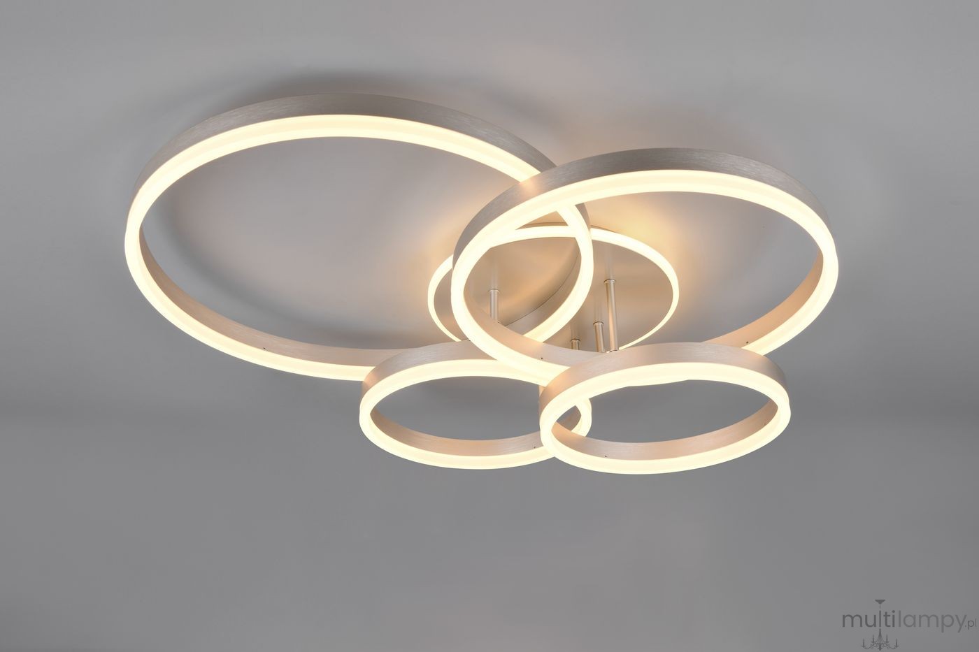 Lampa sufitowa Drake z pilotem, składająca się z czterech okrągłych pierścieni w kolorze niklu, podświetlonych ciepłym światłem LED. Produkt zamontowany na suficie, z widocznymi detalami konstrukcyjnymi.