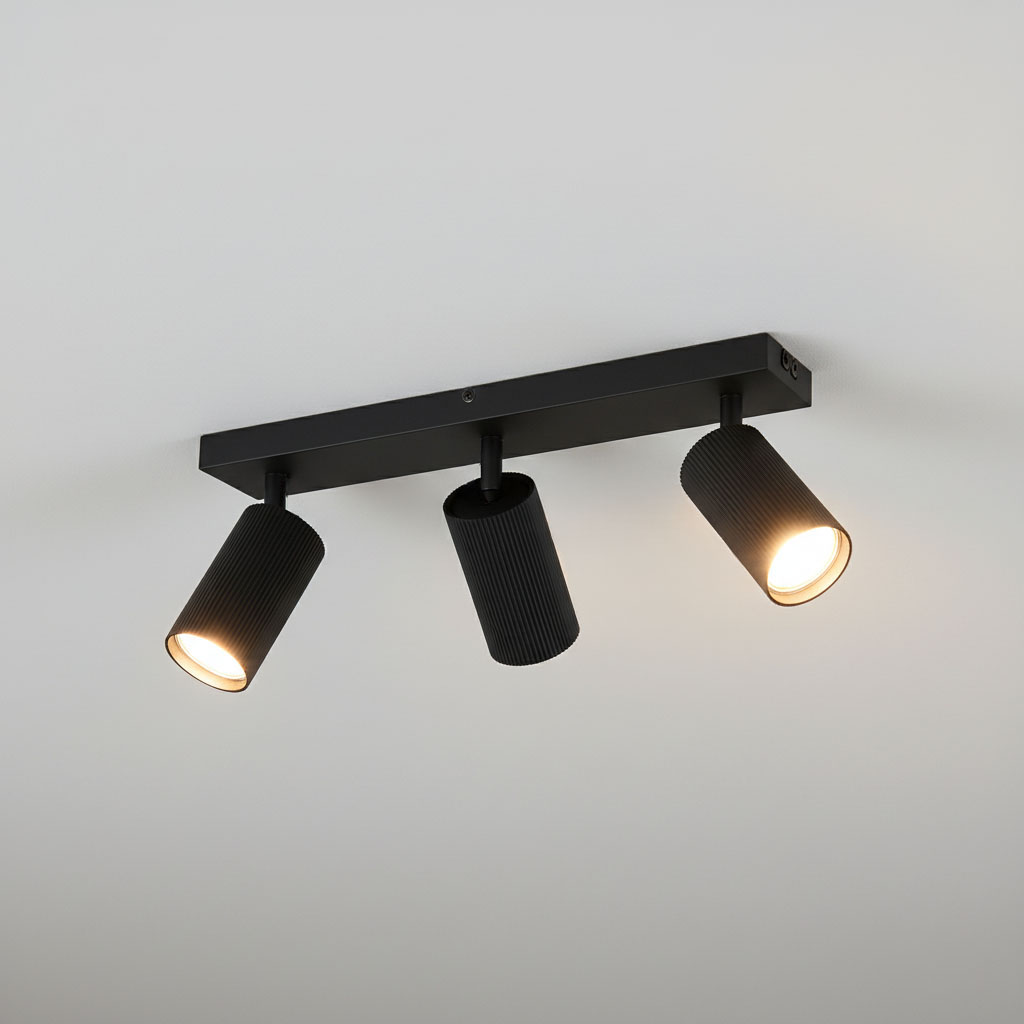 Lampa sufitowa Lucerno w kolorze czarnym z trzema reflektorami GU10, zamontowana na prostokątnej podstawie. Reflektory mają żebrowaną fakturę i są ustawione w różnych kierunkach, emitując ciepłe światło.