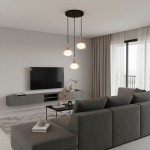 Lampa wisząca Konila 3-punktowa w kolorze czarnym i mosiężnym, z trzema kloszami w kształcie prostokątów, zawieszona na długich linkach. Stylowa, umieszczona w nowoczesnym wnętrzu z szarym sofą i telewizorem na ścianie.