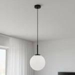 Lampa wisząca Deore D20 z jednym gniazdem E27, w kolorze czarnym i białym. Okrągły klosz z matowego szkła zawieszony na cienkim, czarnym przewodzie. Ujęcie z góry, w jasnym wnętrzu z białymi firanami.