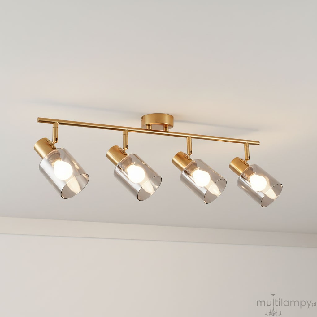 Lampa sufitowa Santia w kolorze mosiądzu z czterema szklanymi kloszami w dymionym odcieniu. Ułożona poziomo, z widocznymi źródłami światła E14. Klosze mają cylindryczny kształt, montaż na suficie. Tło jasne, minimalistyczne.