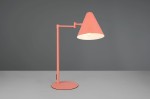 Lampa stołowa Cosima w kolorze morelowym, z metalowym, stożkowatym kloszem. Ustawiona na okrągłej podstawie, z ruchomym ramieniem. Widoczne pojedyncze źródło światła E14. Tło w odcieniu szarości, co podkreśla kolor lampy.