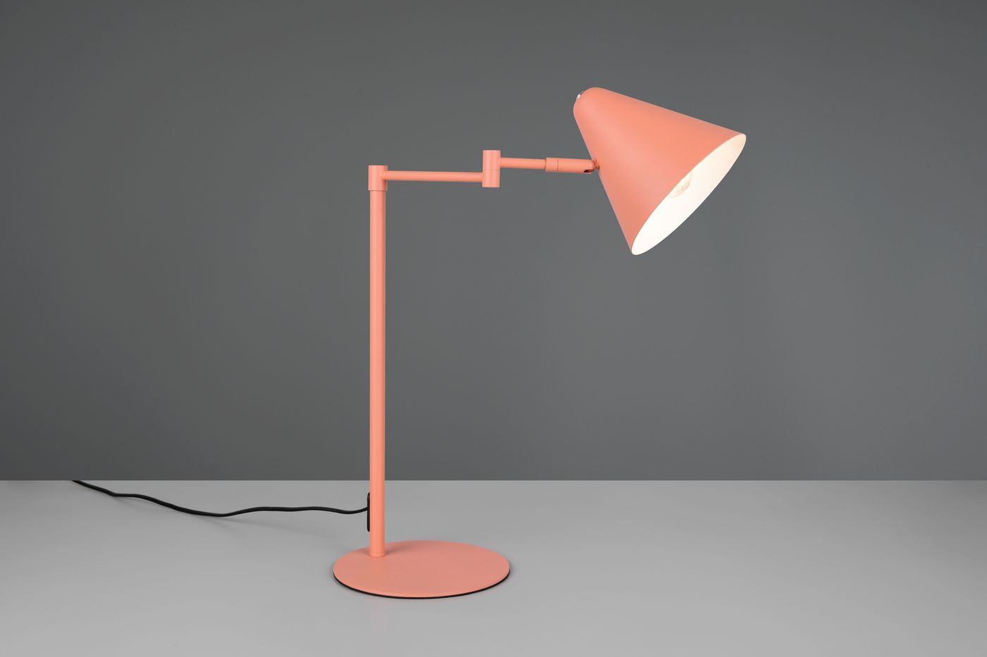 Lampa stołowa Cosima w kolorze morelowym z regulowanym kloszem w kształcie stożka, metalowa podstawa okrągła, cienki stelaż. Ujęcie z boku, na szarym tle, widoczny kabel zasilający.