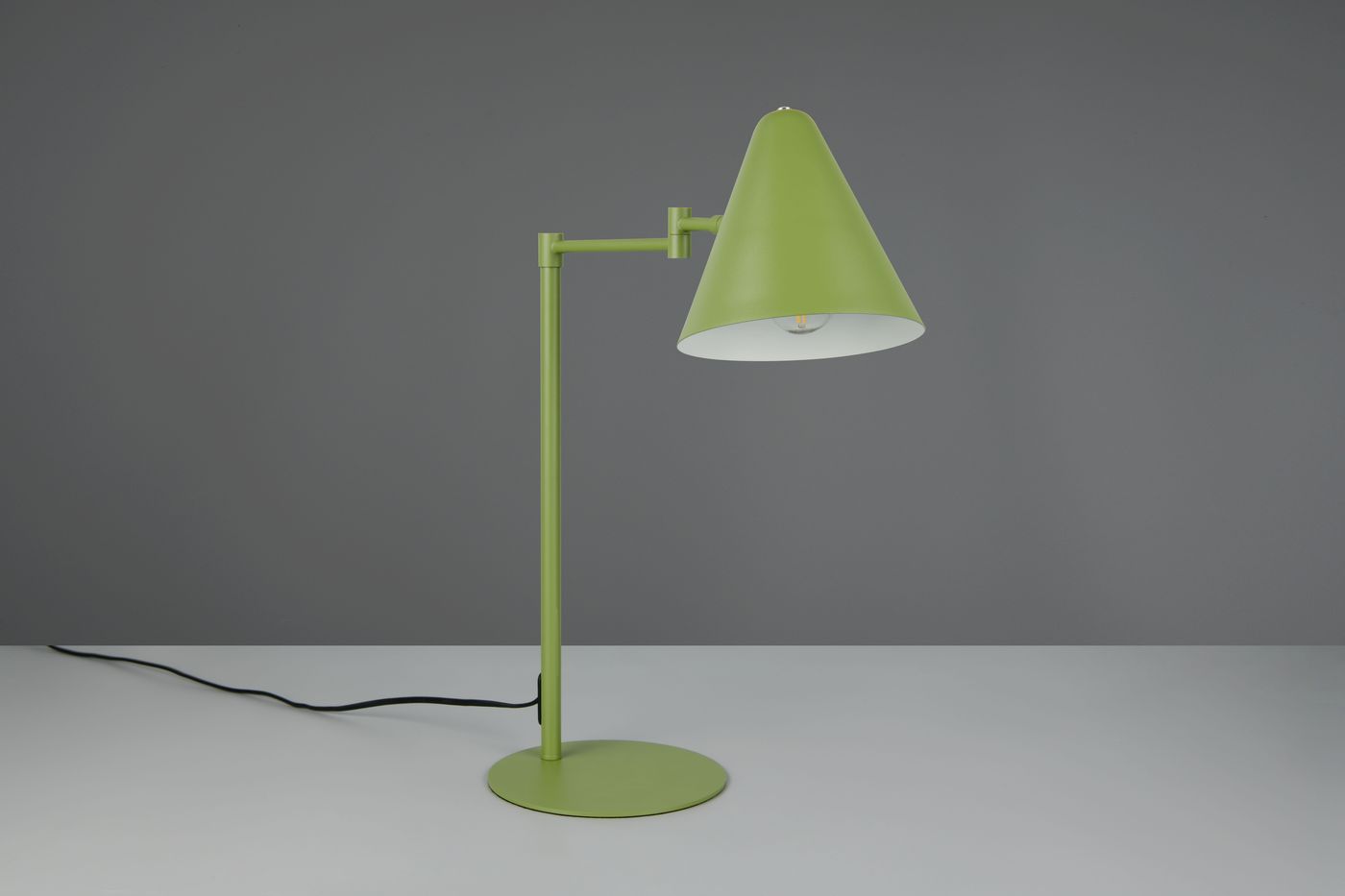 Lampa stołowa Cosima w kolorze zielonym z kloszem w kształcie stożka i metalową podstawą. Ujęcie z boku, ukazujące regulowaną konstrukcję i przewód zasilający. Idealna do oświetlenia biurka lub stolika.