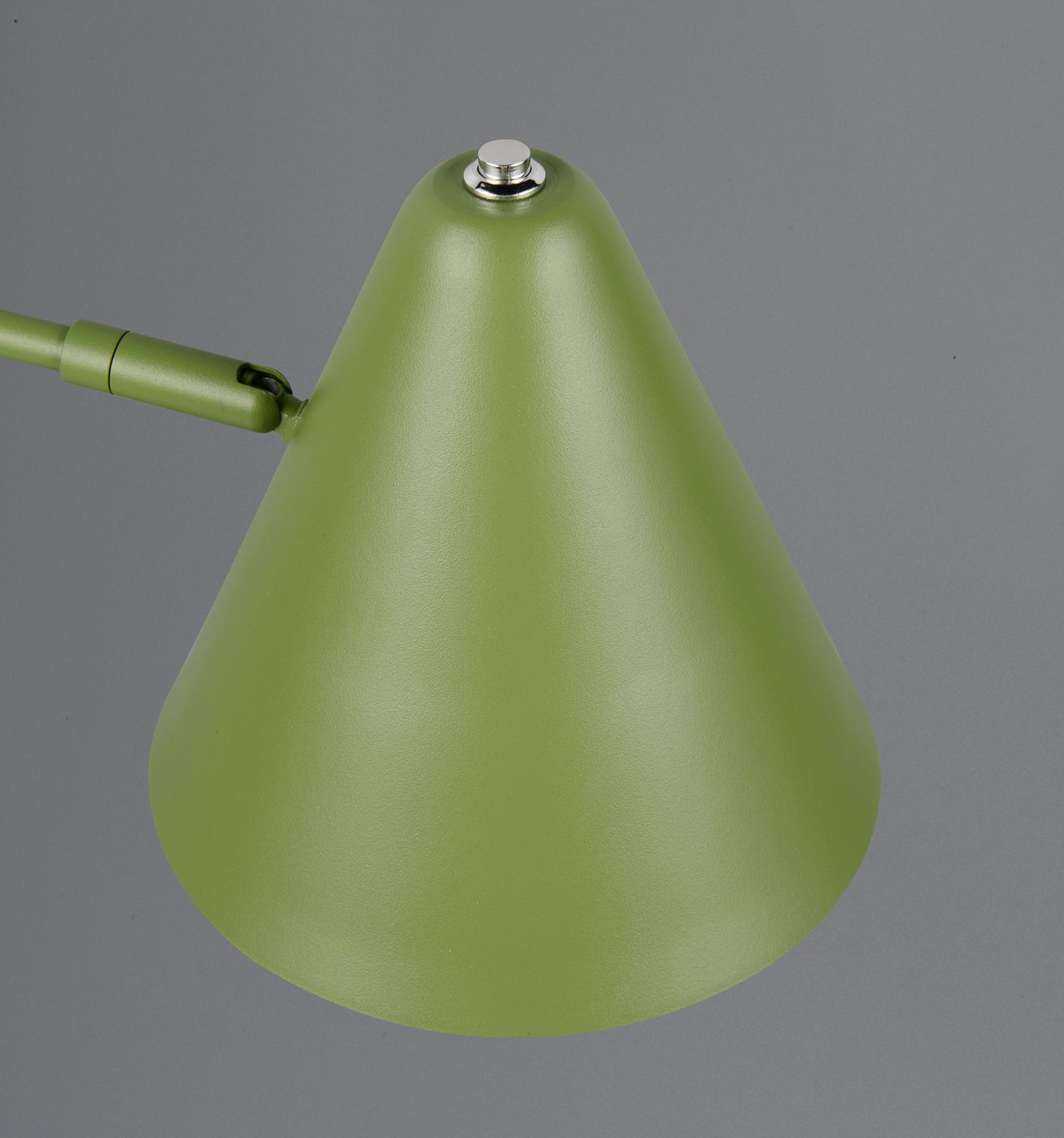 Lampa stołowa Cosima w zielonym kolorze z kloszem w kształcie stożka. Klosz wykonany z matowego materiału, z metalowym przyciskiem na górze. Ujęcie z boku, ukazujące detal konstrukcji.