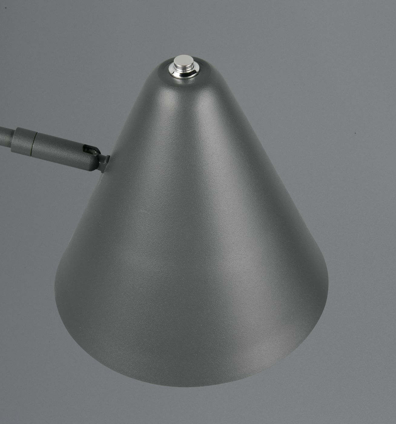 Lampa stołowa Cosima w antracytowym kolorze z kloszem o stożkowym kształcie. Widoczny metalowy przycisk na górze oraz miejsce na żarówkę E14. Ujęcie z góry, na jednolitym tle.
