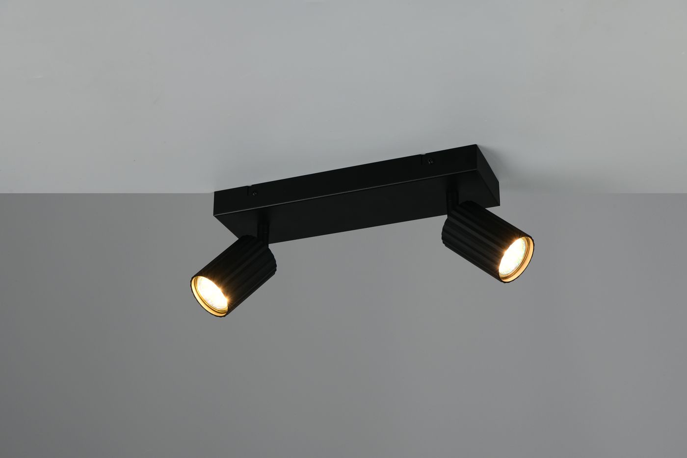 Lampa sufitowa Soka w kolorze czarnym z dwoma ruchomymi punktami świetlnymi GU10. Ułożona poziomo, montowana na suficie, z widocznymi cylindrycznymi kloszami o teksturowanej powierzchni.
