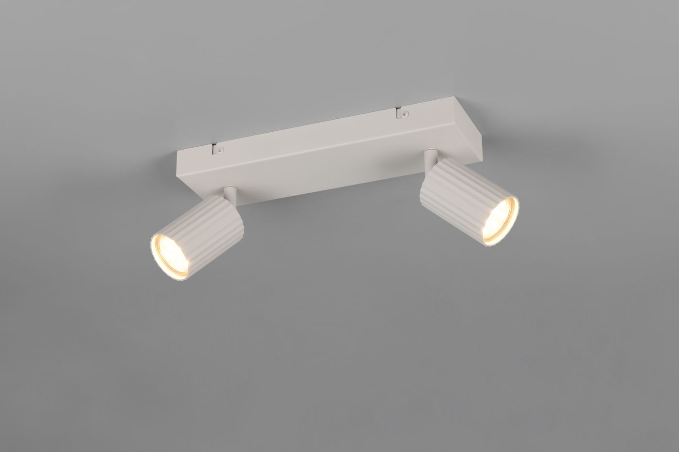 Lampa sufitowa Soka w kolorze szarym z dwoma reflektorami typu GU10. Ujęcie z góry, na prostokątnej podstawie, z cylindrycznymi kloszami o żebrowanej fakturze. Reflektory skierowane w różnych kierunkach, montowane na suficie.