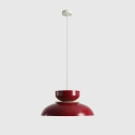 Lampa wisząca Aldo, 1xE27, w kolorze czerwonego wina. Posiada elegancki, zaokrąglony klosz z matowego metalu oraz mniejszą, okrągłą podstawę. Zawieszona na długim przewodzie, idealna do nowoczesnych wnętrz. Tło jasne, minimalistyczne.