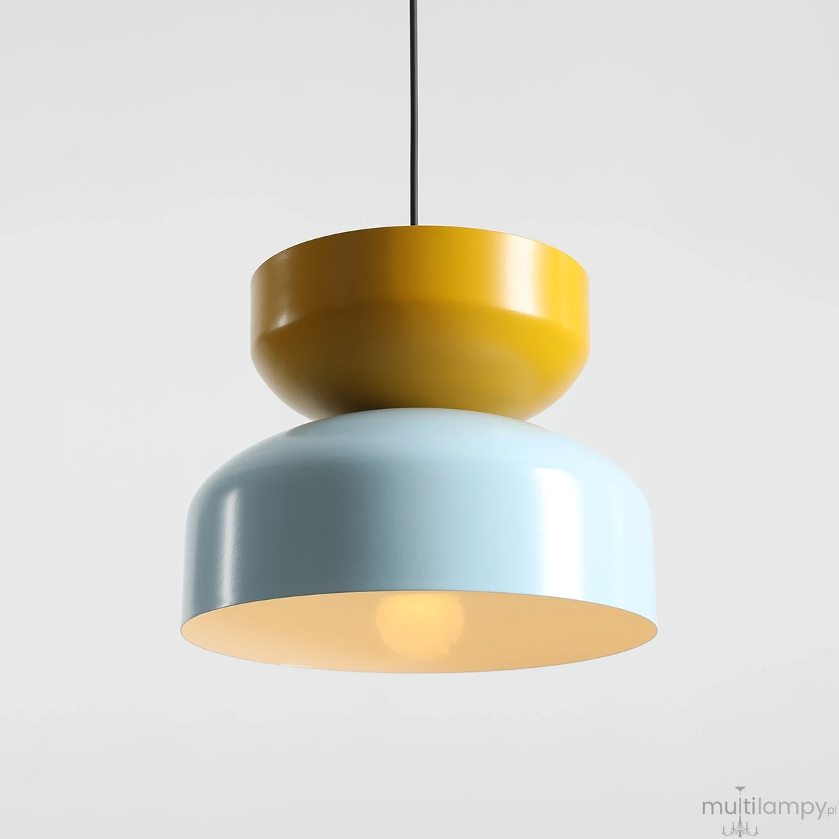 Lampa wisząca Tula z jednym gniazdem E27, w kolorze baby blue i musztardowym. Składa się z dwóch połączonych cylindrycznych elementów: dolnego w błękitnym odcieniu i górnego w musztardowym. Zawieszona na czarnym przewodzie, idealna do nowoczesnych wnętrz.