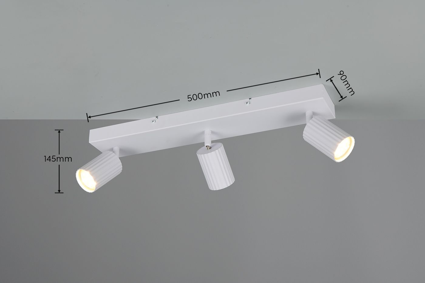 Biała lampa sufitowa z trzema reflektorami GU10, montowana na płaskiej podstawie. Wymiary: długość 500 mm, wysokość 145 mm, szerokość 90 mm. Reflektory o teksturowanej, cylindrycznej obudowie, skierowane w różnych kierunkach. Tło szare.
