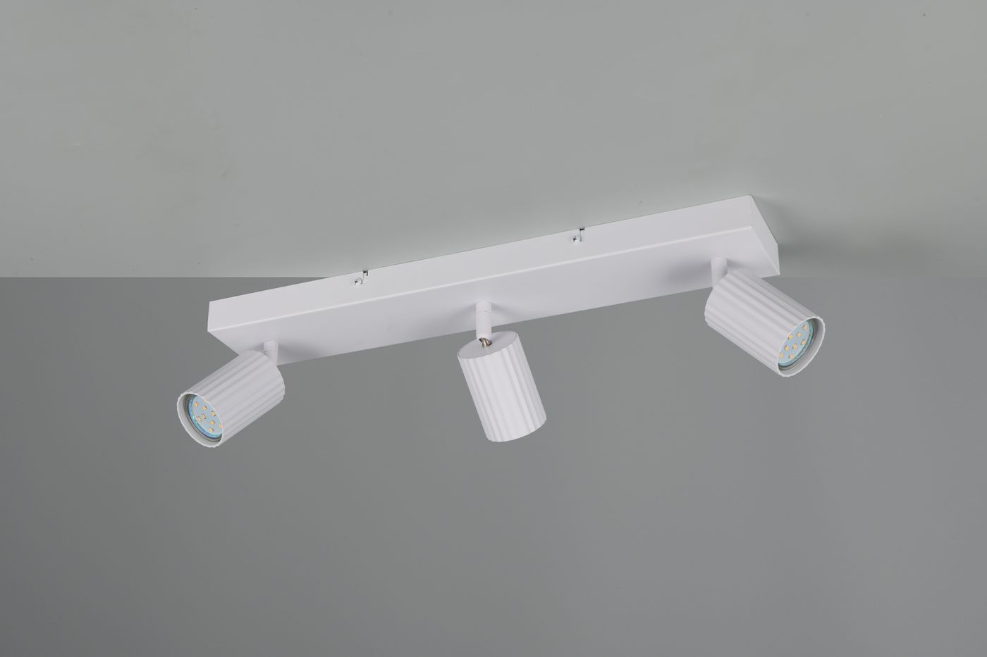 Lampa sufitowa Soka w białym kolorze z trzema ruchomymi reflektorami na prostokątnej podstawie. Reflektory mają żebrowaną fakturę i są przystosowane do żarówek GU10. Ujęcie z góry, przedstawiające montaż sufitowy.