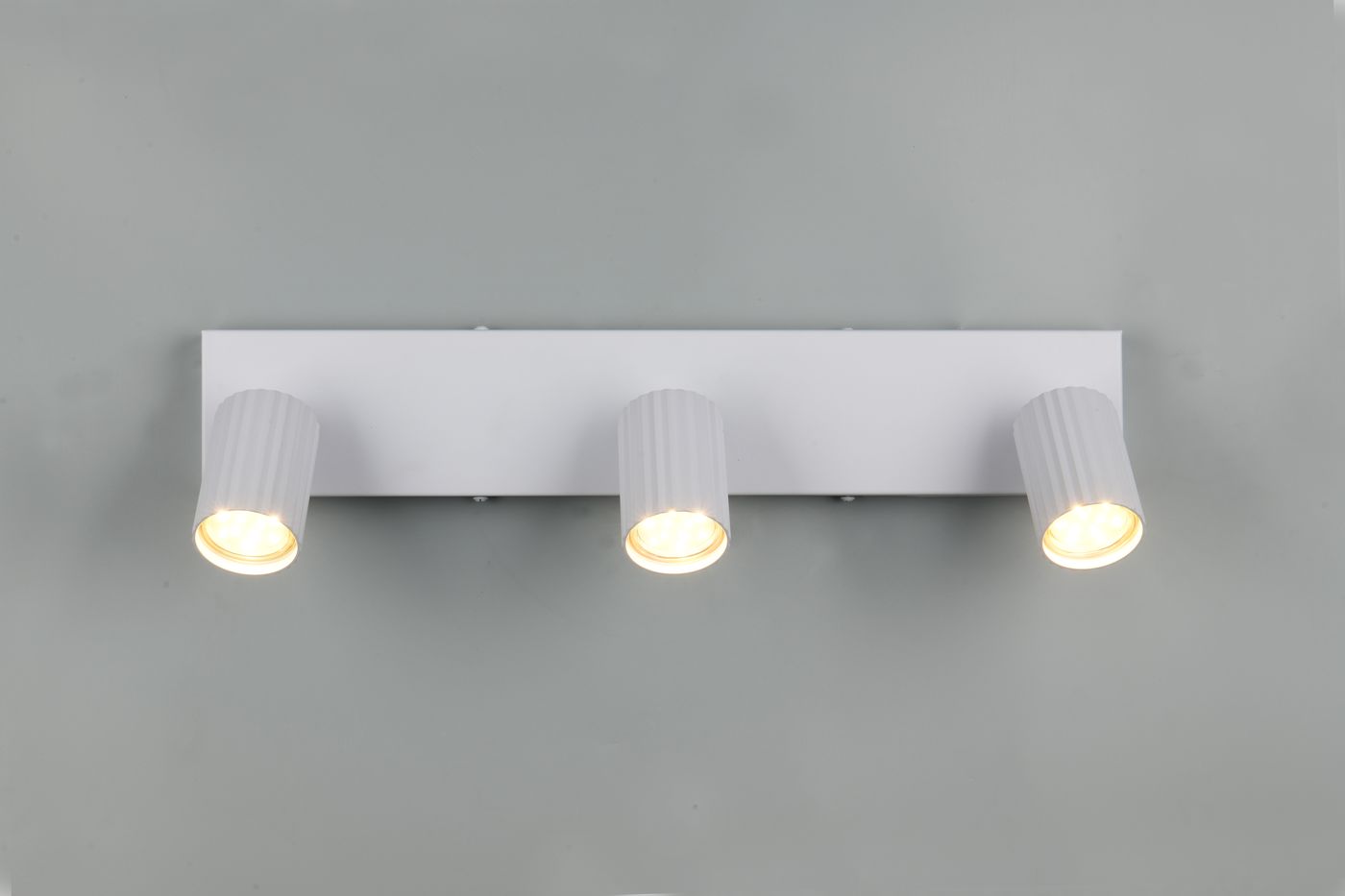 Lampa sufitowa Soka z trzema reflektorami GU10, zamontowana na prostokątnej, białej podstawie. Reflektory mają żłobioną fakturę i emitują ciepłe światło. Ujęcie frontalne, na jednolitym tle.