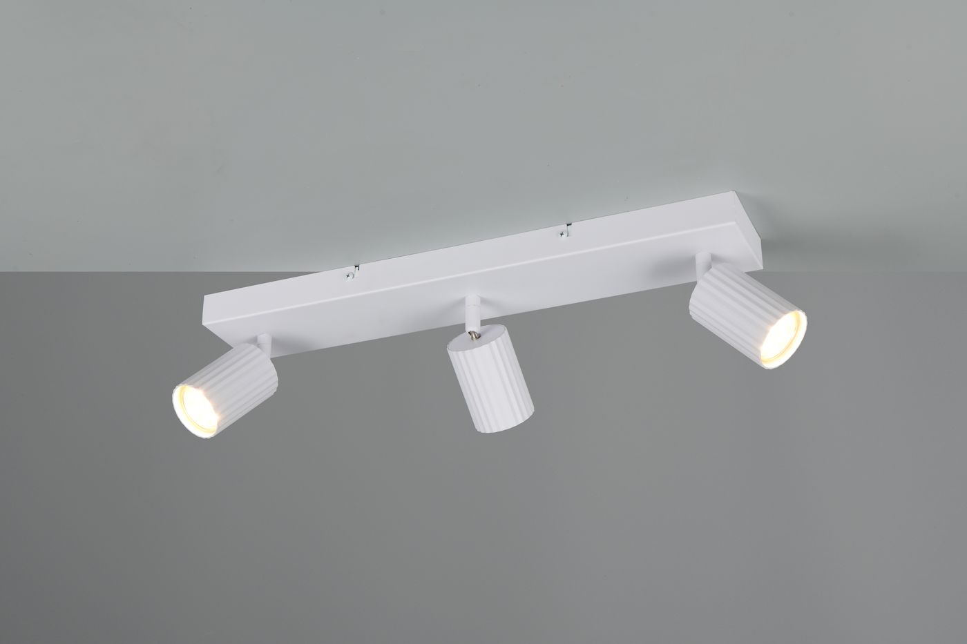 Lampa sufitowa Soka z trzema reflektorami GU10 w kolorze białym, zamontowana na prostokątnej podstawie. Reflektory mają żebrowaną teksturę i są ustawione pod różnymi kątami, co umożliwia skierowanie światła w różnych kierunkach.
