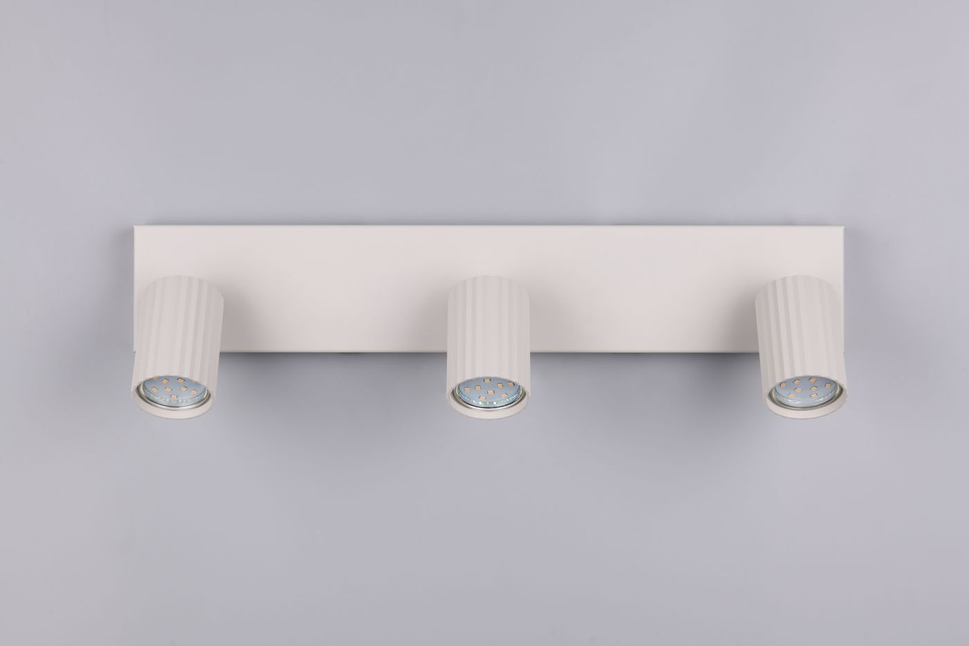 Lampa sufitowa Soka z trzema reflektorami GU10 w szarym kolorze. Prosta, prostokątna konstrukcja z rowkowanymi kloszami, zamontowana na gładkiej podstawie. Reflektory są skierowane lekko w dół, co umożliwia regulację oświetlenia.