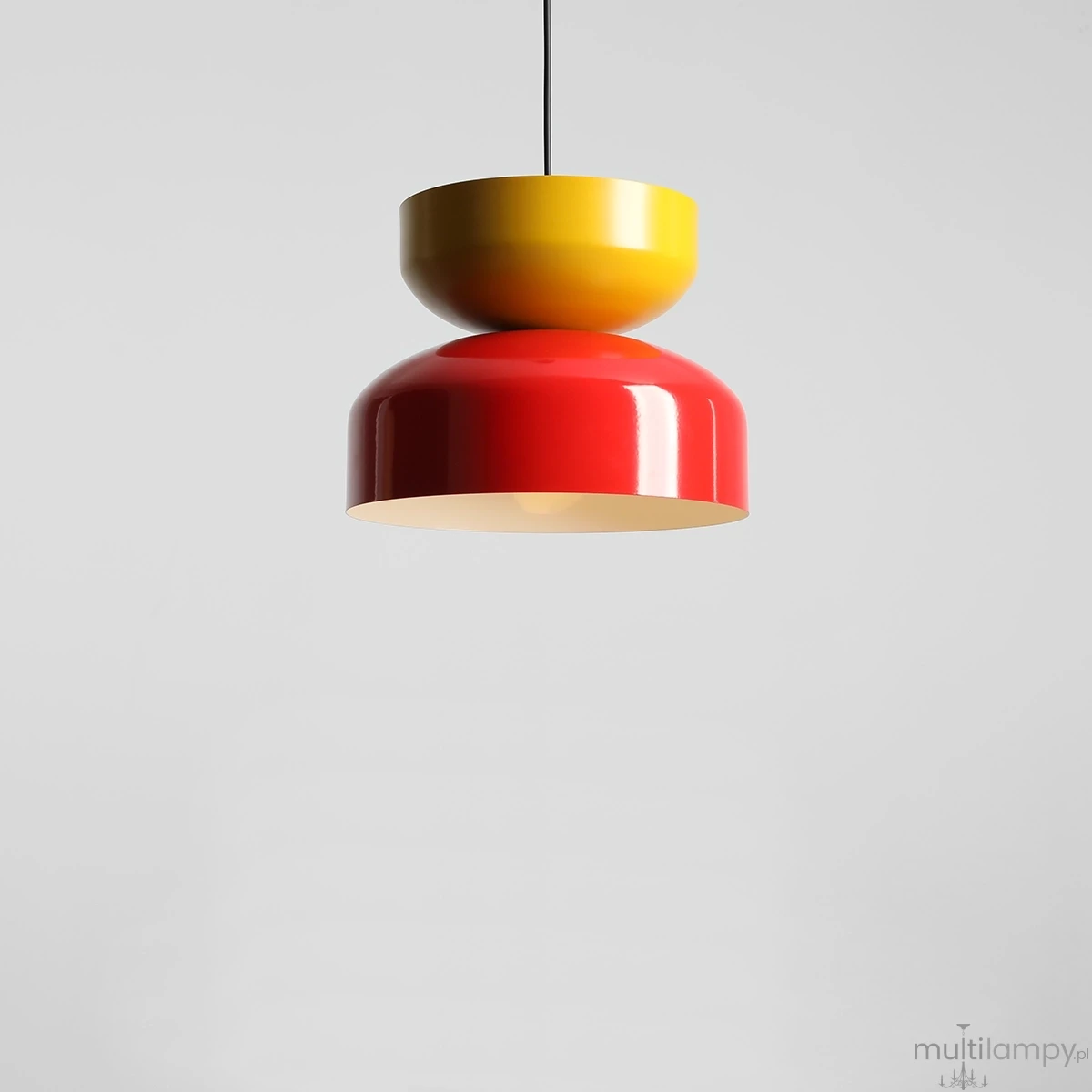 Lampa wisząca Tula z jednym gniazdem E27 w kolorach czerwonym chili i musztardowym. Okrągła, błyszcząca konstrukcja z górnym, żółtym kloszem oraz dolnym, czerwonym kloszem, zawieszona na czarnym przewodzie. Tło jasnoszare.