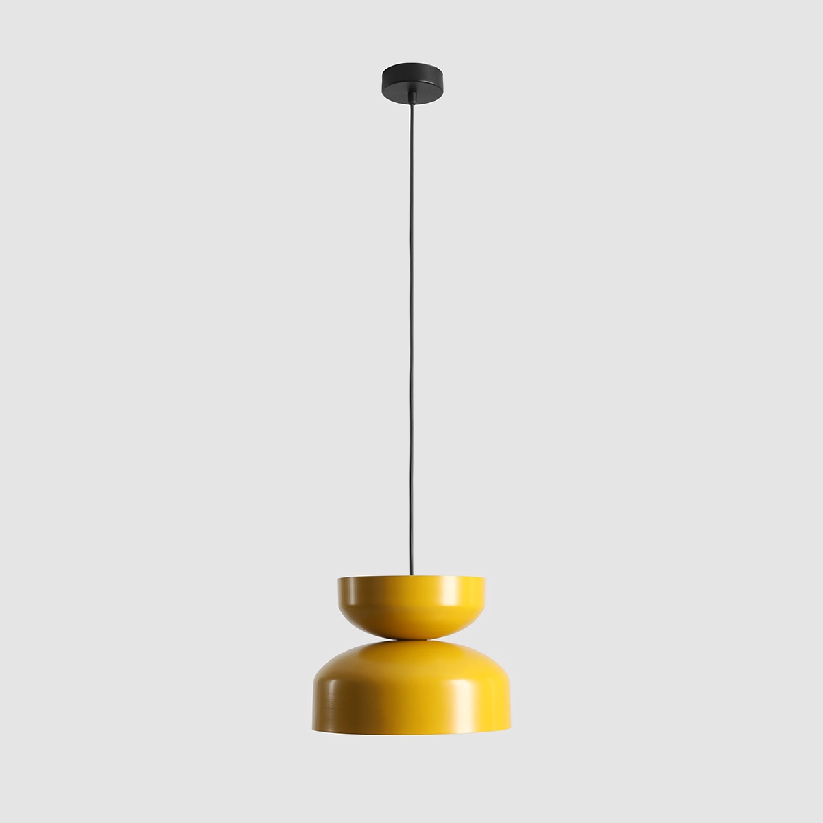 Lampa wisząca Tula w kolorze musztardowym, z metalowym kloszem o dwóch połączonych elementach: górnym cylindrycznym i dolnym półkulistym. Zawieszona na czarnym przewodzie, zamontowana na prostokątnej, czarnej podstawie, na jednolitym tle.