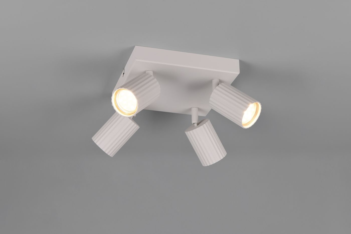 Lampa sufitowa Soka z czterema reflektorami GU10 w szarym kolorze, umieszczona na kwadratowej podstawie. Reflektory o żłobionej fakturze są regulowane, co umożliwia skierowanie światła w różnych kierunkach.