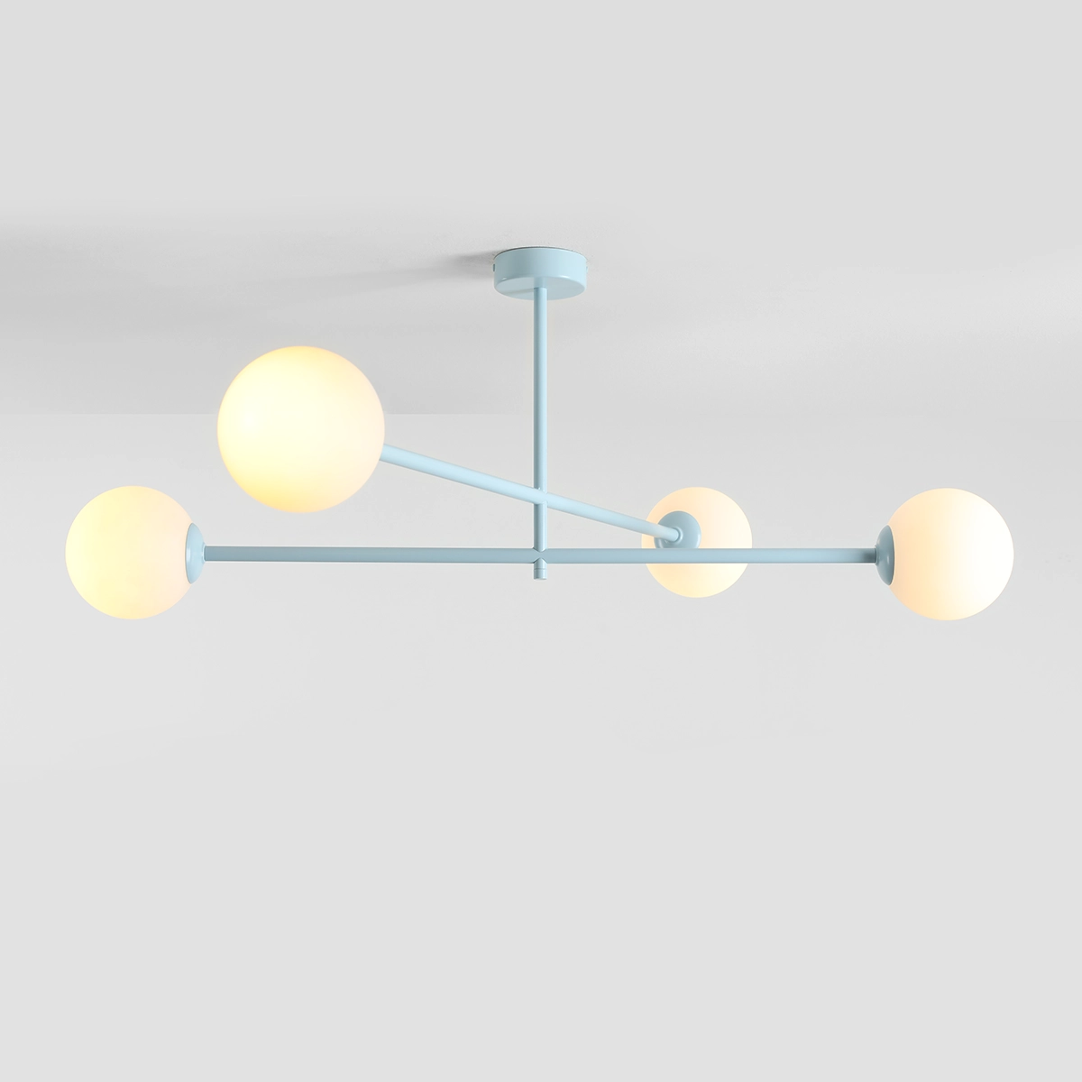 Pinne lampa sufitowa w kolorze błękitnym z czterema okrągłymi kloszami, zamocowana na cienkim stelażu. Klosze emitują ciepłe światło, a całość zawieszona jest na suficie w frontalnej pozycji.