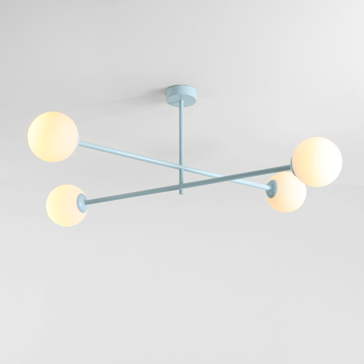 Lampa sufitowa Pinne w kolorze błękitnym, z czterema okrągłymi kloszami w kolorze białym. Elementy metalowe w formie prostych ramion, utrzymane w minimalistycznym stylu. Zamontowana na suficie, prezentuje nowoczesny design.