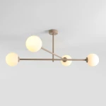 Beżowa lampa sufitowa Pinne z czterema kulistymi, mlecznymi kloszami na metalowej konstrukcji. Ujęcie z dołu, pokazujące równomiernie rozmieszczone źródła światła na ramionach lampy. Tło białe, co podkreśla kolor i kształt lampy.