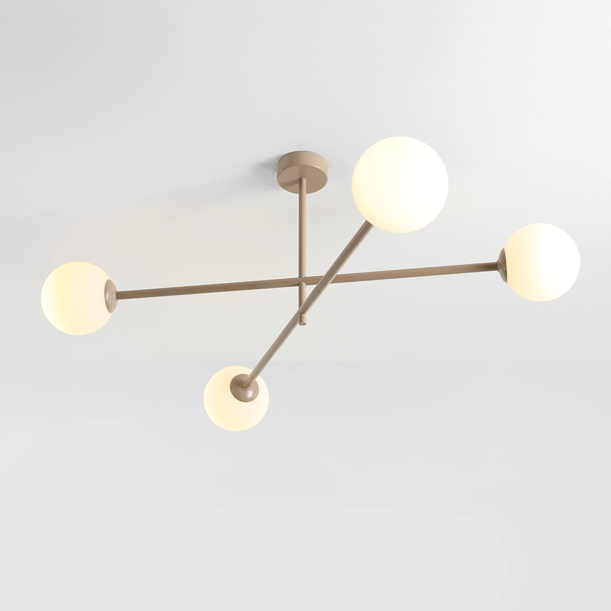 Beżowa lampa sufitowa Pinne z czterema oprawami E14, w kształcie krzyża, z matowym wykończeniem. Szklane klosze w formie kul, umieszczone na cienkich metalowych ramionach. Lampa montowana na suficie, w minimalistycznym stylu.
