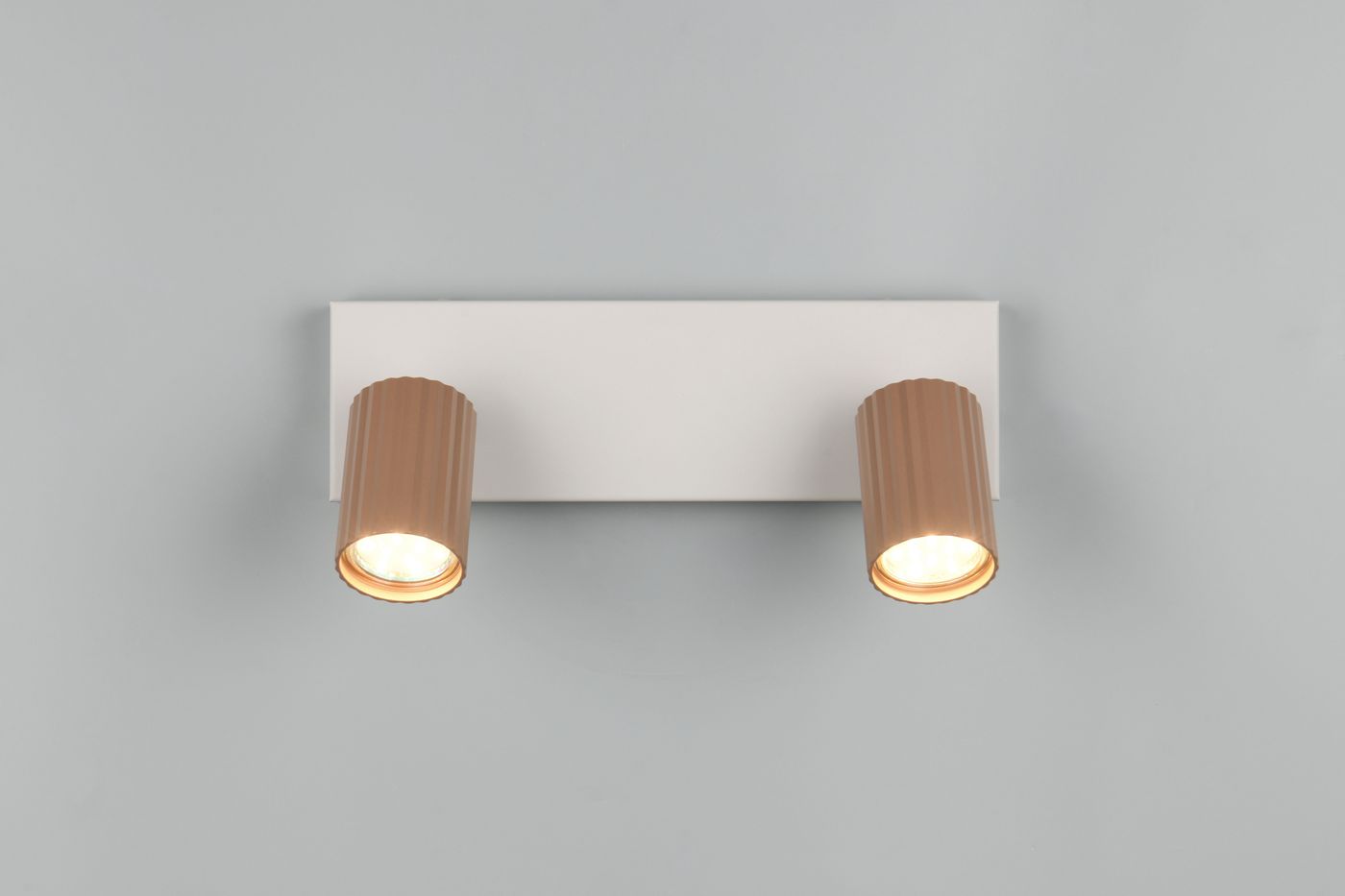 Lampa sufitowa Soka w kolorze szarym z dwoma reflektorami GU10 w odcieniu kawowym. Ujęcie frontalne, produkt zamontowany na ścianie, z wyraźnymi żłobieniami na obudowie reflektorów i równą, prostokątną podstawą.