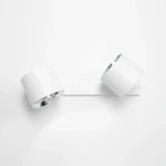 Kinkiet 2-punktowy w kolorze białym, zamontowany na prostokątnej podstawie. Dwa okrągłe klosze z metalicznymi detalami, skierowane w różnych kierunkach. Prosty, nowoczesny design na jednolitym tle.