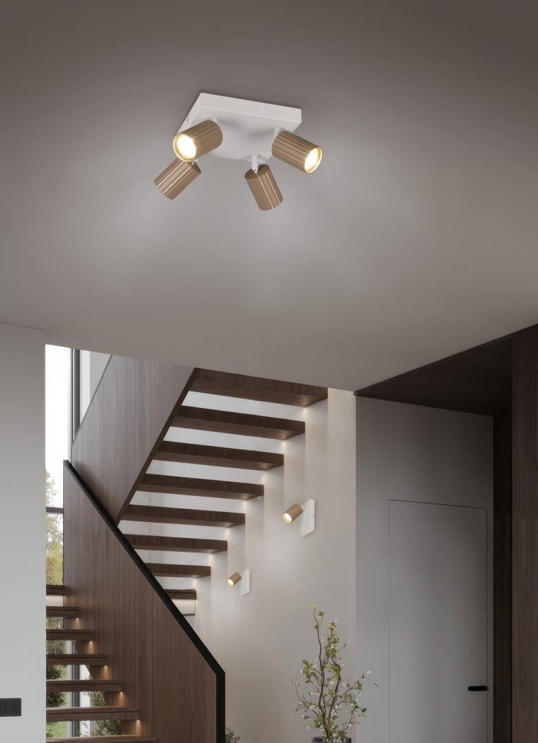 Lampa sufitowa Soka w kolorze szaro-kawowym z czterema reflektorami GU10. Reflektory w kształcie cylindrów, zamontowane na prostokątnej bazie. Produkt umieszczony w nowoczesnym wnętrzu z widoczną klatką schodową w tle.