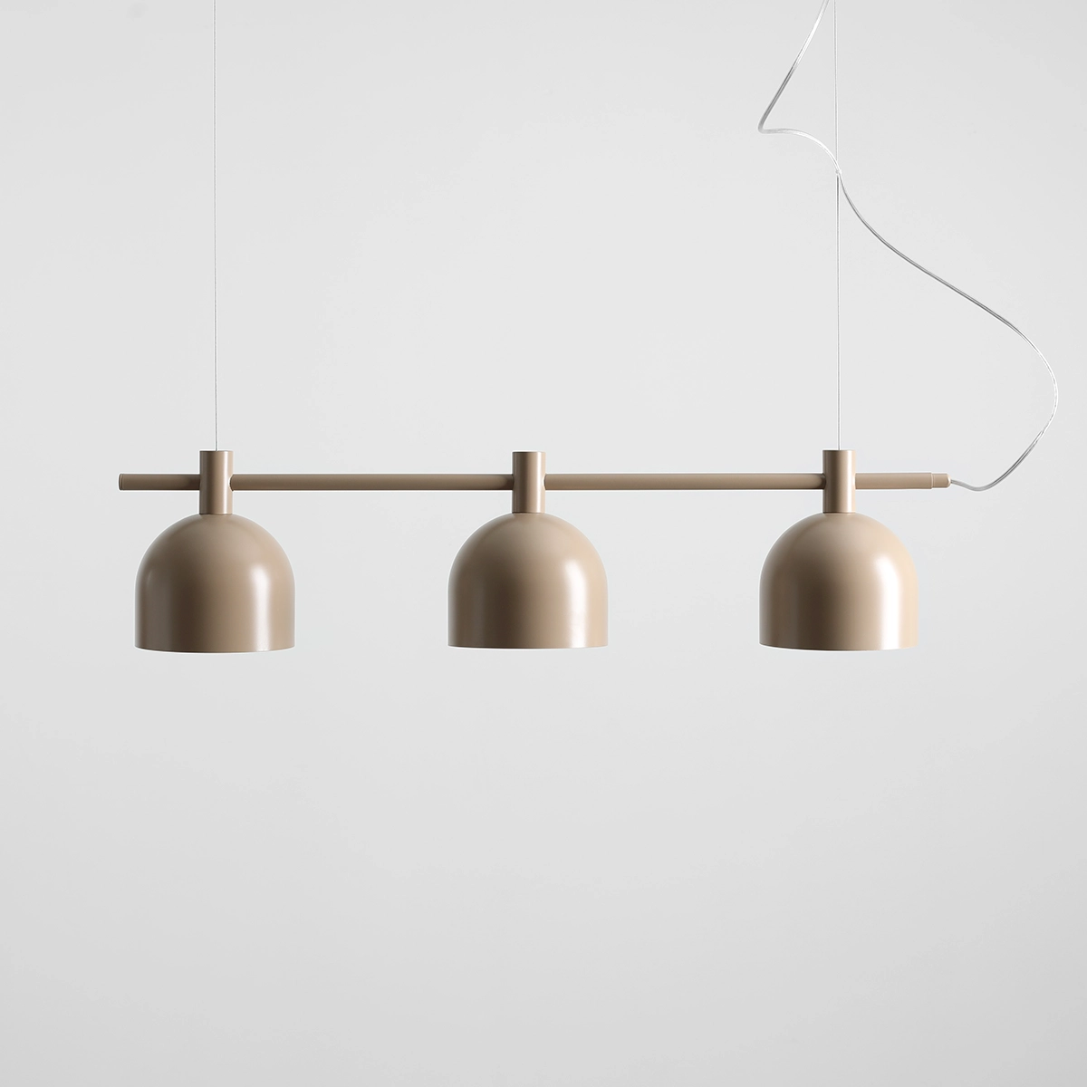 Lampa wisząca Beryl w kolorze beżowym z trzema kloszami o kształcie półkulistym, zawieszona na poziomej rurze. Wisi na cienkim przewodzie, idealna do nowoczesnych wnętrz.