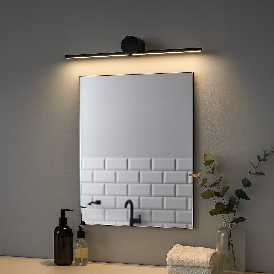 Kinkiet Artist L40,5 LED 6W 4000K IP44 w kolorze czarnym, umieszczony nad prostokątnym lustrem. Oświetlenie emituje ciepłe światło, a w tle widoczne są kosmetyki oraz elementy aranżacji łazienki na gładkiej, jasnej ścianie.