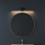 Kinkiet Artist L40,5 LED 6W 4000K w kolorze czarnym, montowany nad okrągłym lustrem. Oświetlenie punktowe, minimalistyczny design, z okrągłym elementem mocującym. Tło w ciemnym kolorze, lampa emituje ciepłe światło.