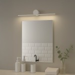 Kinkiet Artist L40,5 LED 6W 4000K IP44 w kolorze białym, zamontowany nad lustrem. Oświetlenie punktowe w minimalistycznym stylu, z okrągłym mocowaniem i prostokątną lampą, w jasnym wnętrzu z elementami białej cegły. W tle kosmetyki i roślinność.