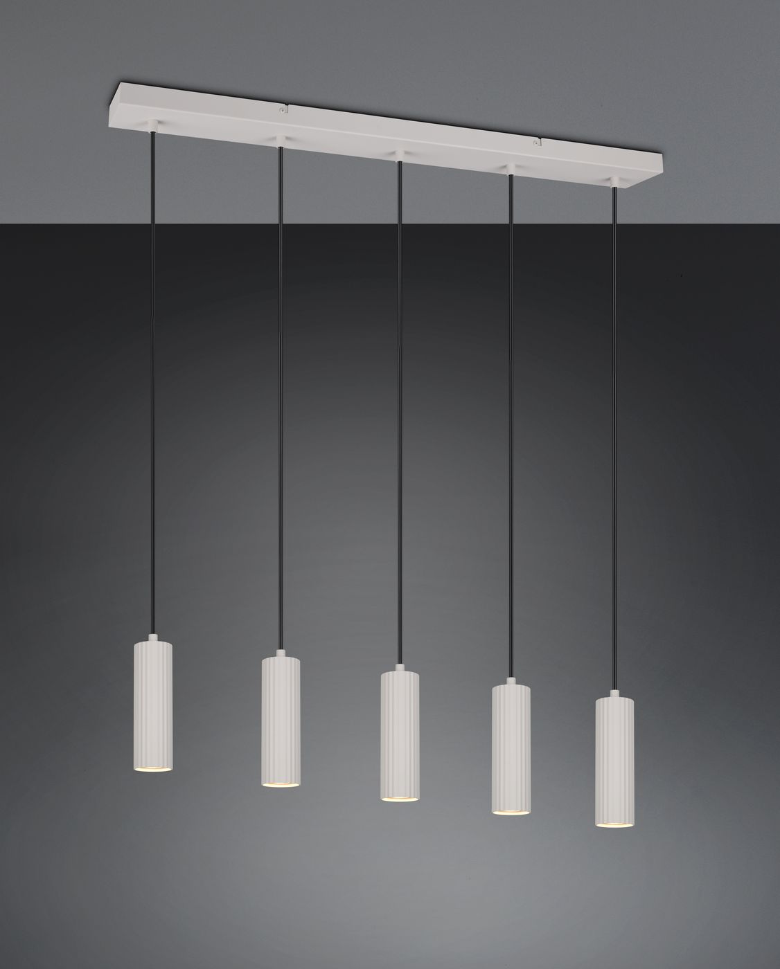 Lampa wisząca Soka z pięcioma oprawami GU10 w szarym kolorze. Cylindryczne klosze z białego materiału zawieszone na czarnych przewodach, zamontowane na prostokątnej bazie. Ujęcie frontalne, na jednolitym tle.