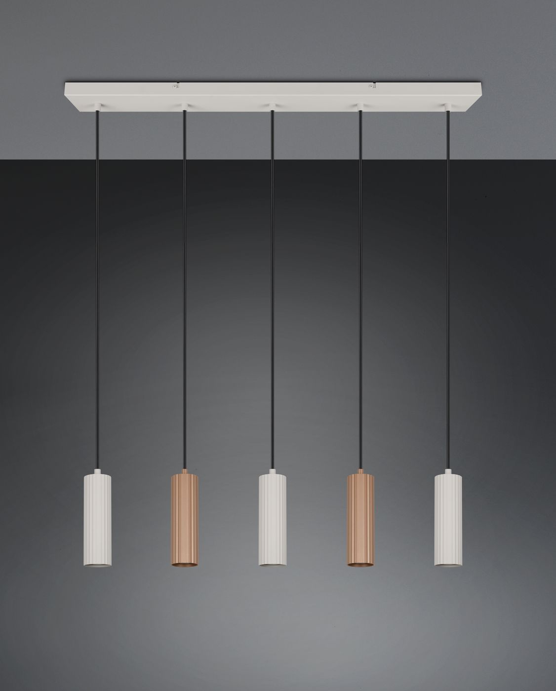 Lampa wisząca Soka z pięcioma oprawami GU10 w kolorze szarym i kawowym. Elementy mają cylindryczny kształt, zawieszone na czarnych przewodach. Montaż na prostokątnej, białej podstawie. Tło w odcieniu ciemnoszarym.